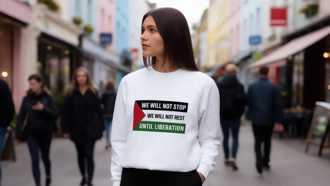 Woman in a white We Will Not Stop sweatshirt over a grey long sleeve on a street in Notting Hill, London