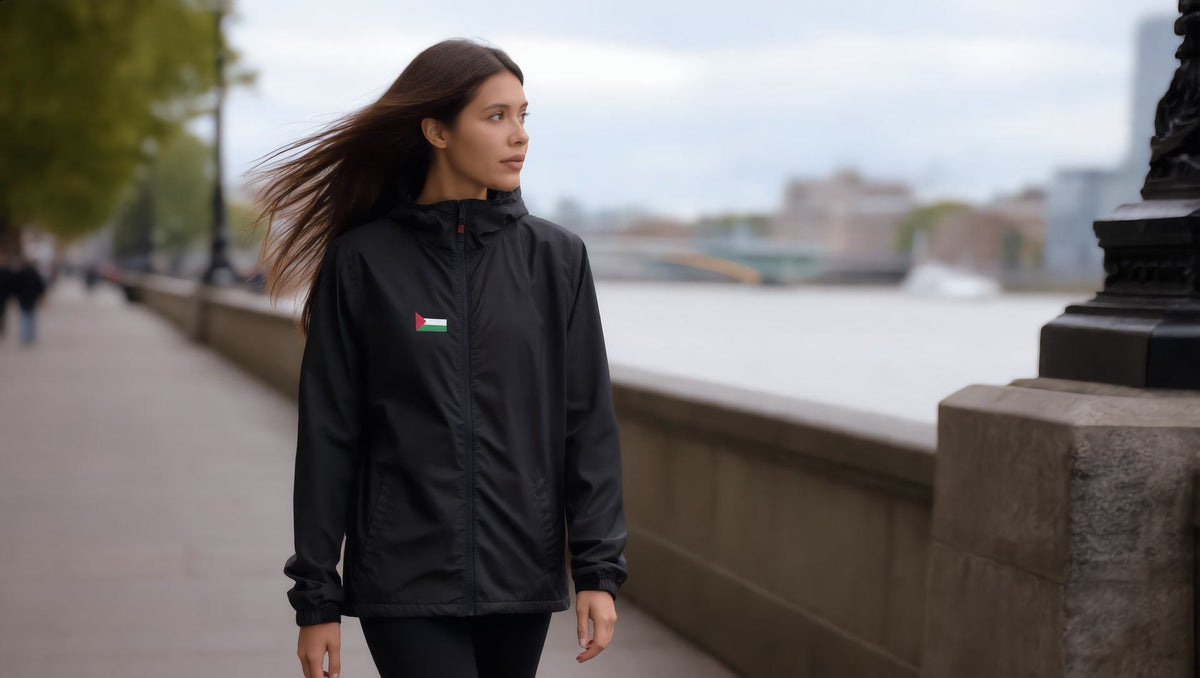 Woman wearing a black windbreaker with a small Palestine flag by the Thames, London